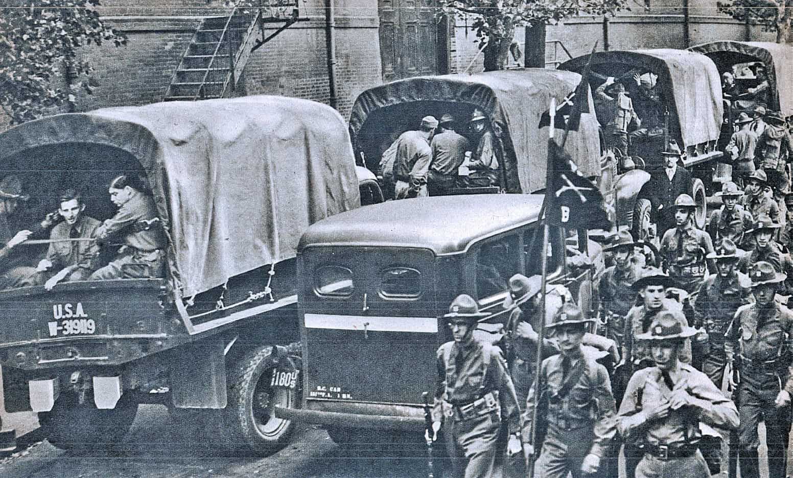 Vintage military trucks and soldiers during wartime, historical black-and-white image showcasing U.S. military during a significant era.