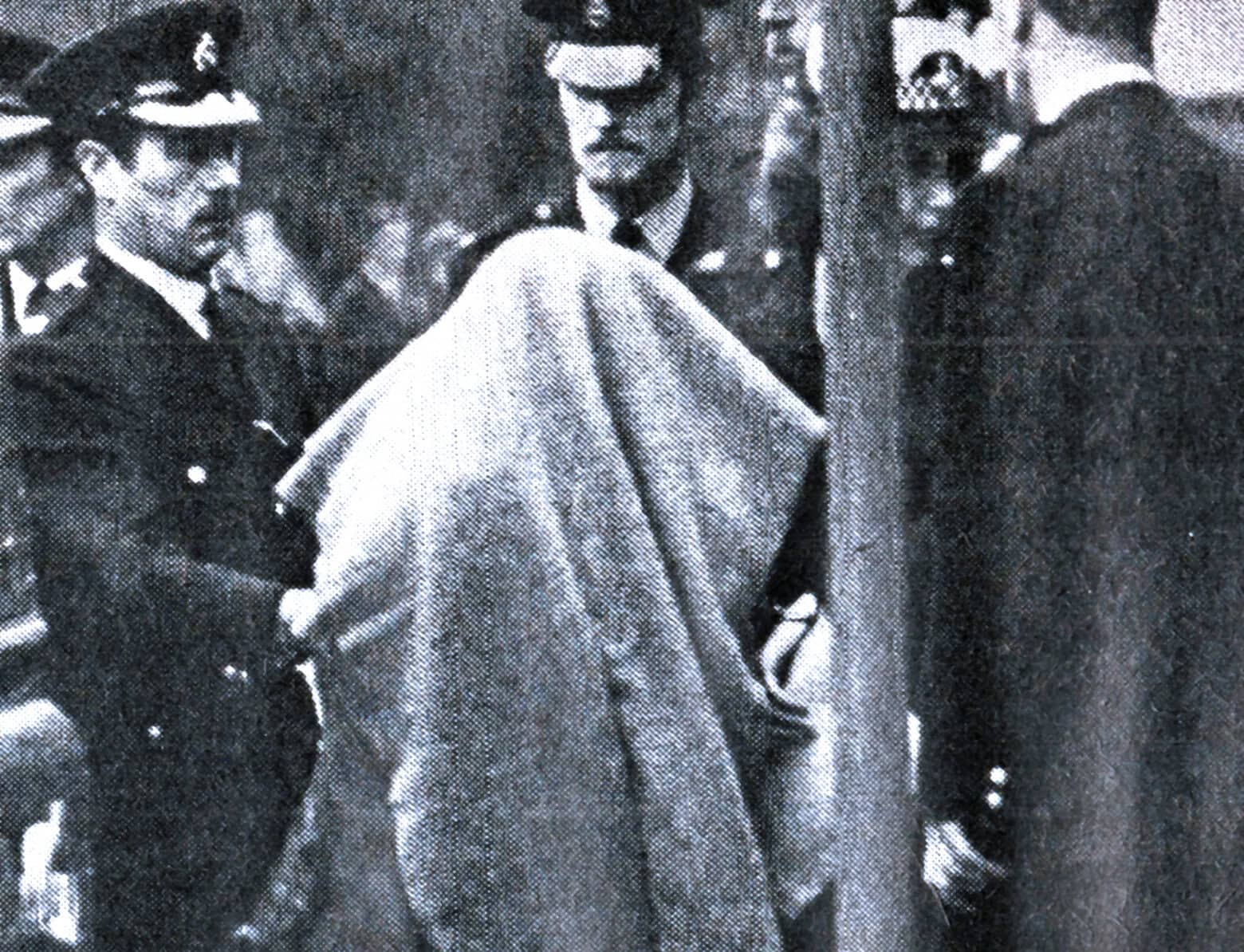 Black and white historical photo of civil rights protest, police officers, and a woman holding a cloth, capturing a moment of social justice movement and activism.