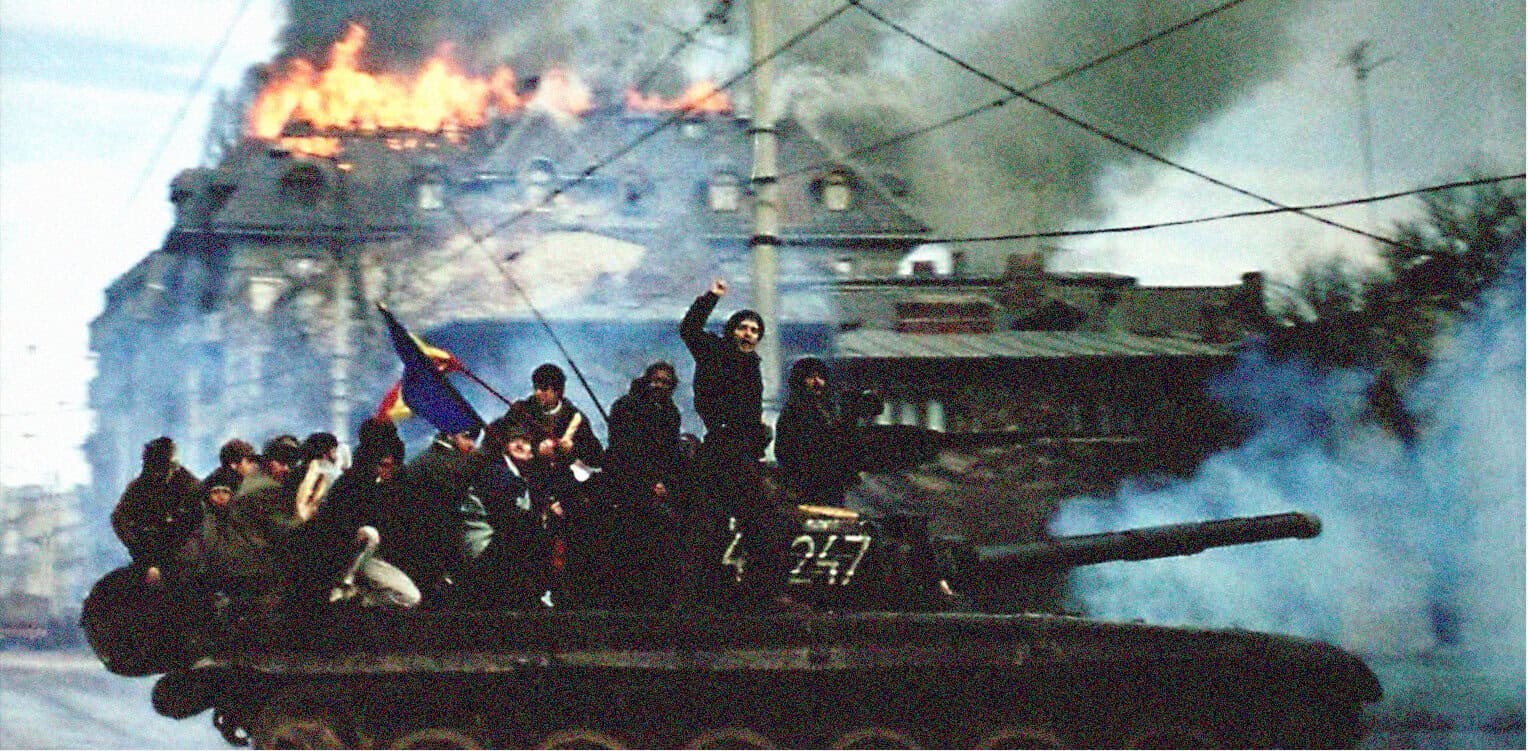 Tank with armed protesters during a conflict, with smoke and flames, highlighting unrest and historical significance.