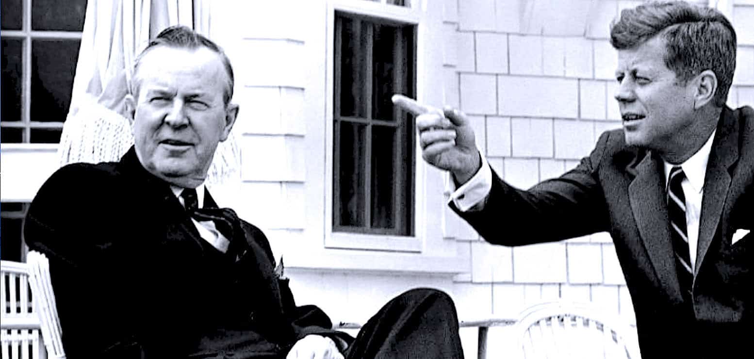 Historical black and white photo of John F. Kennedy and Robert F. Kennedy engaging in political discussion at an outdoor setting.