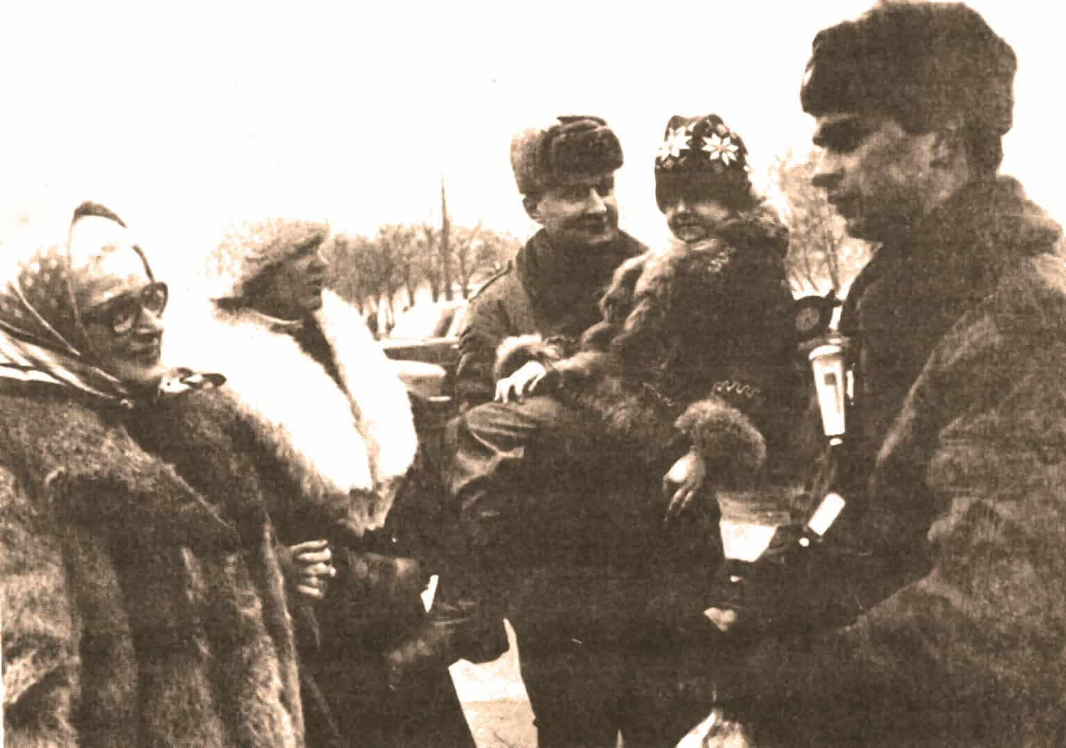 Vintage black and white photo of people dressed warmly, engaging in an outdoor conversation. Perfect for archives about historical events, community stories, or vintage news features.