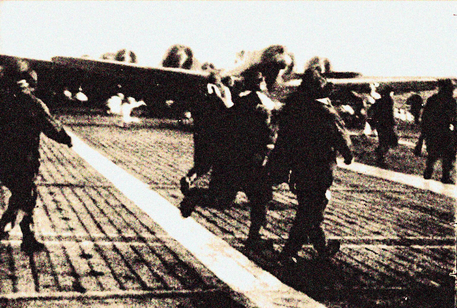 Historic black and white photo of workers and officials on a cobblestone street during a significant historical event, possibly related to social or political history.