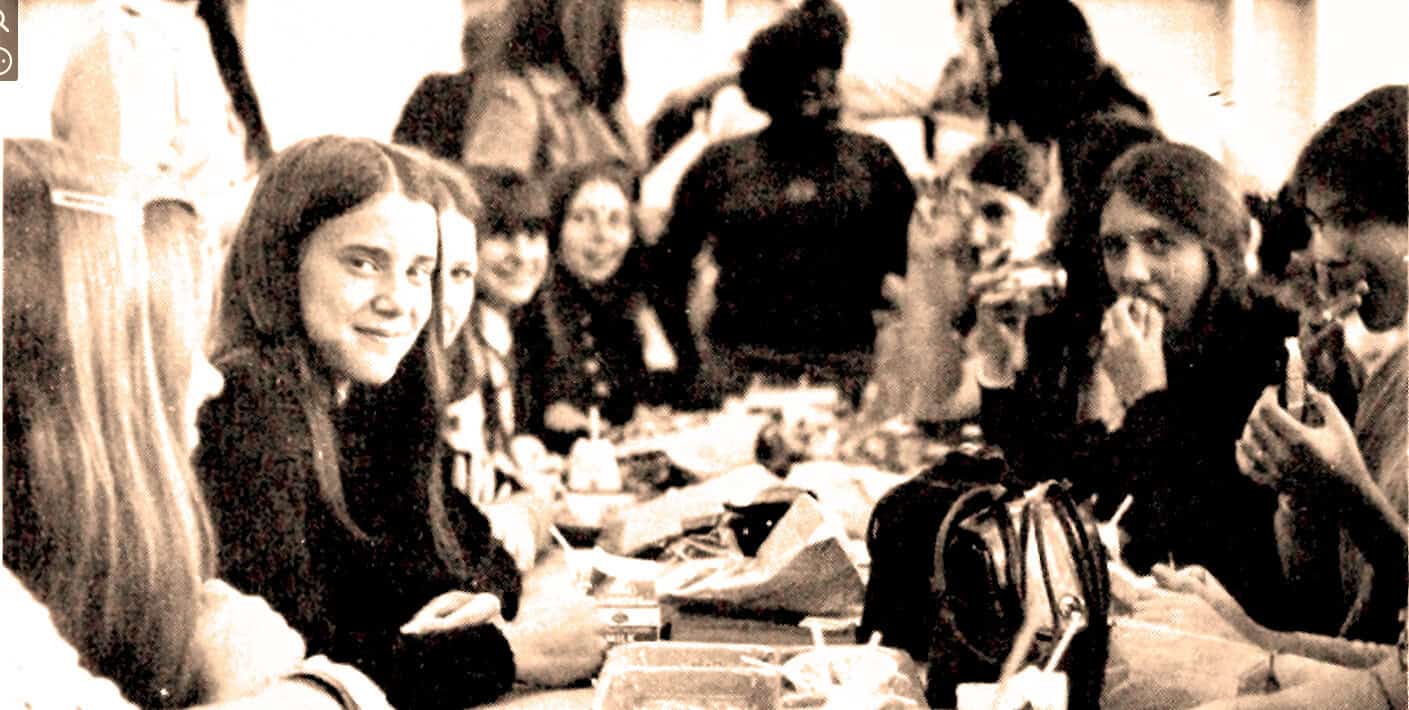 Vintage black-and-white photo of a diverse group of people enjoying music and conversation at a social gathering.