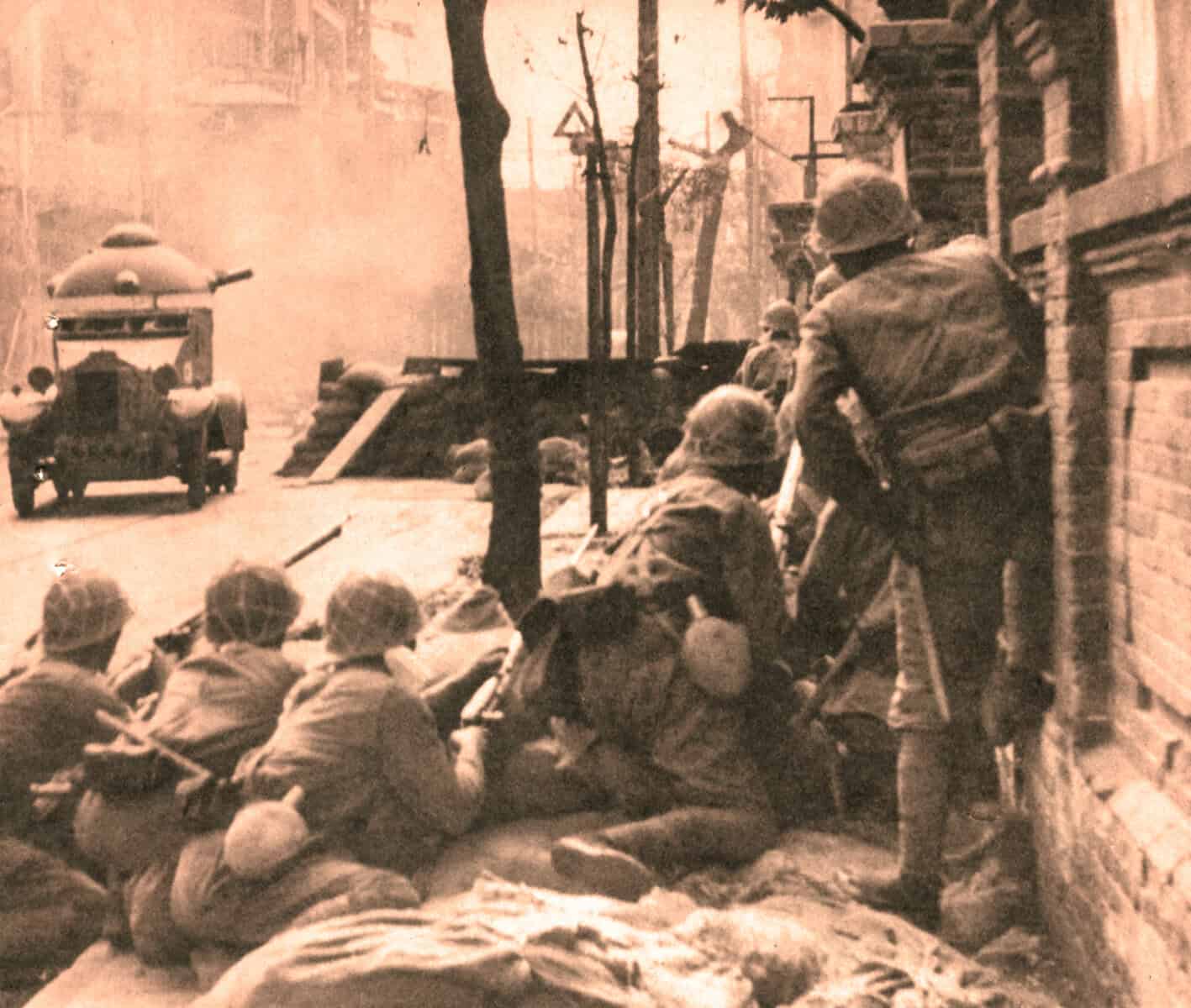 Soldiers resting on a city street during wartime, historical military scene, vintage war photo, soldiers with helmets and gear, urban war zone environment.
