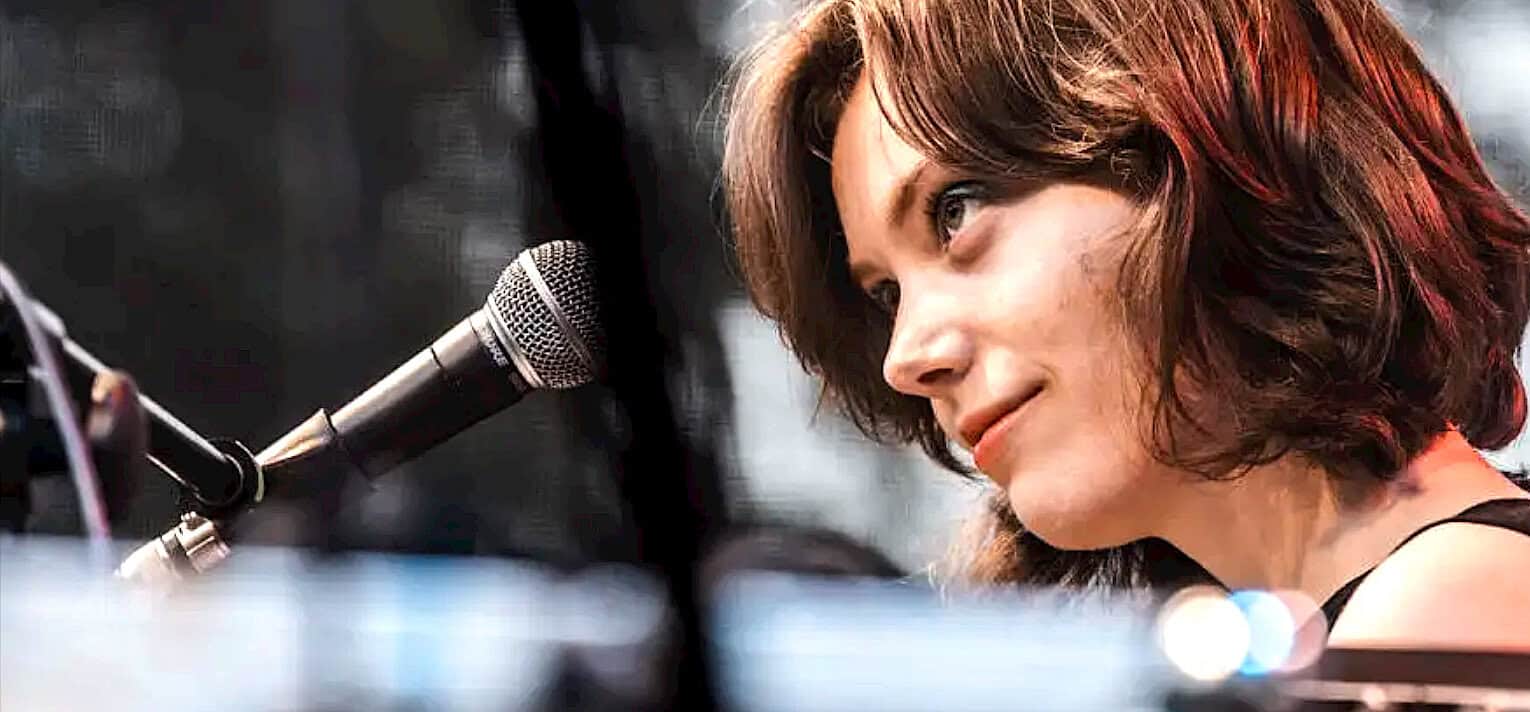 Female singer at microphone in recording studio, music performance, close-up of woman with short brown hair singing and auditioning.