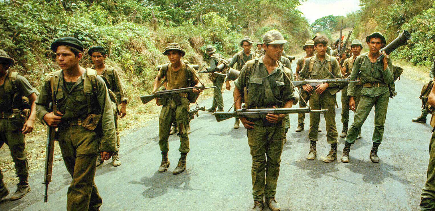 Soldiers marching with rifles in a jungle setting, part of historical military news coverage.