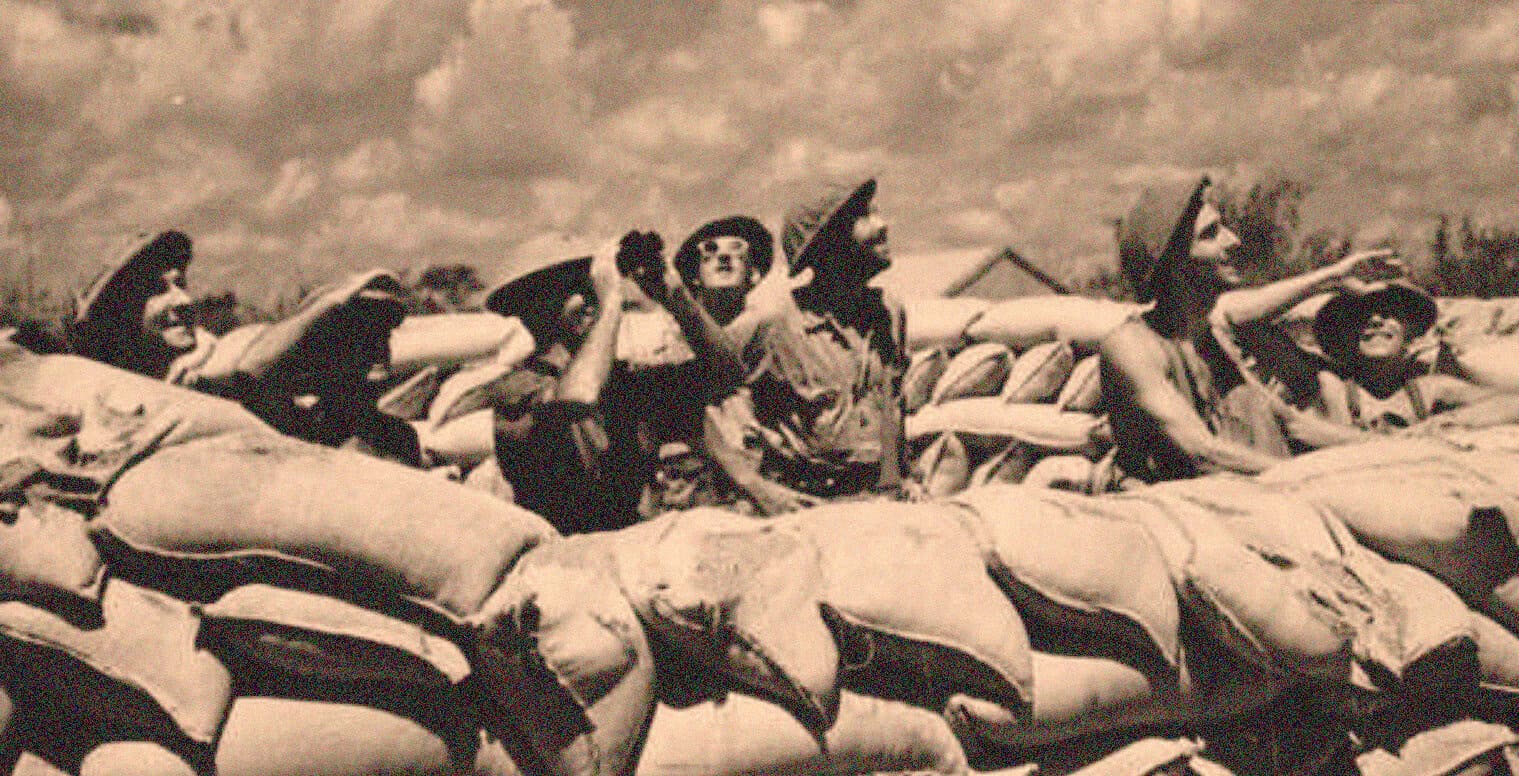Children dressed as soldiers, sitting on sandbags during wartime, portraying historical military scenes with a vintage black and white aesthetic.