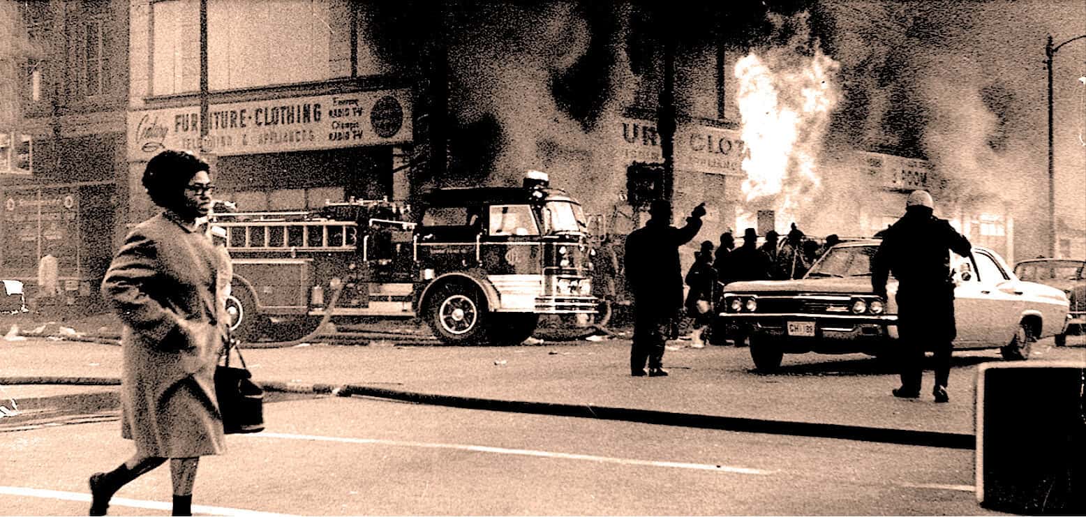 Fire emergency response scene with firefighters, smoke, and civilians on the street.