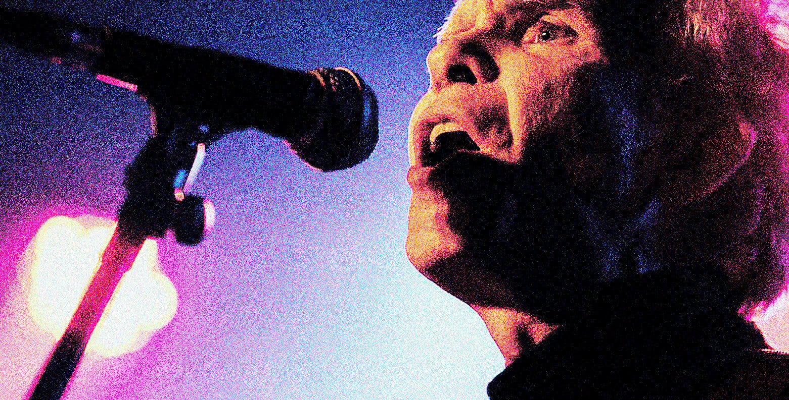 Vintage rock singer performing live at music event, microphone close-up, vibrant stage lighting.