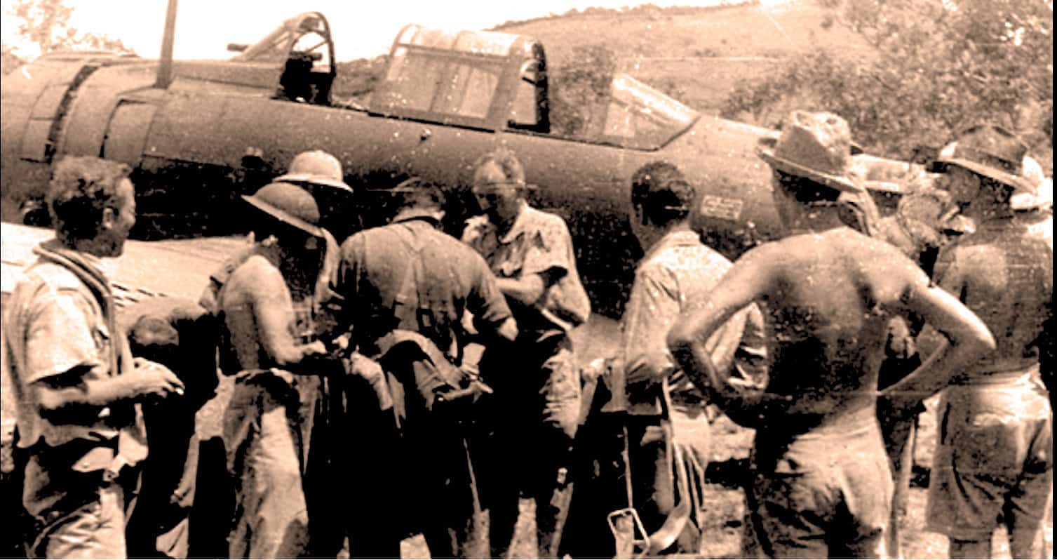 A vintage black and white photo of soldiers around a fighter jet during a war, depicting historical military aviation and wartime scene.