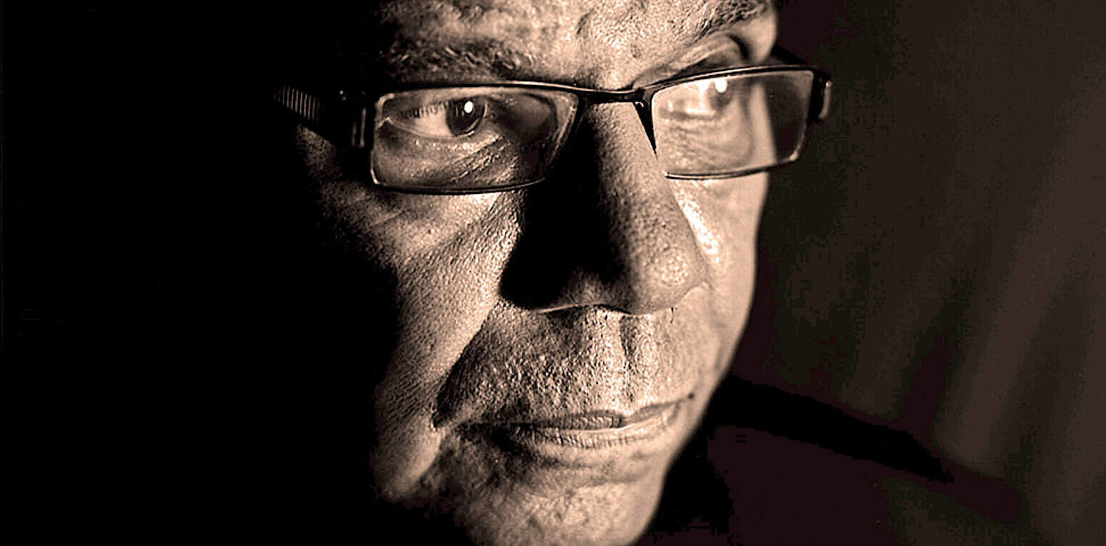Old man wearing glasses, deep in thought, with a contemplative expression highlighting wisdom and experience. Suitable for themes related to history, news archives, and sound recordings.