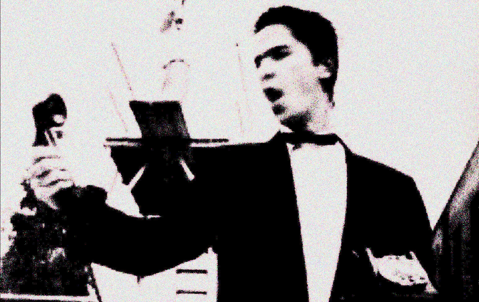 Vintage black and white photo of a man singing with a microphone, capturing a classic music performance. Ideal for music history, news archives, and sound recordings related to Past Daily.