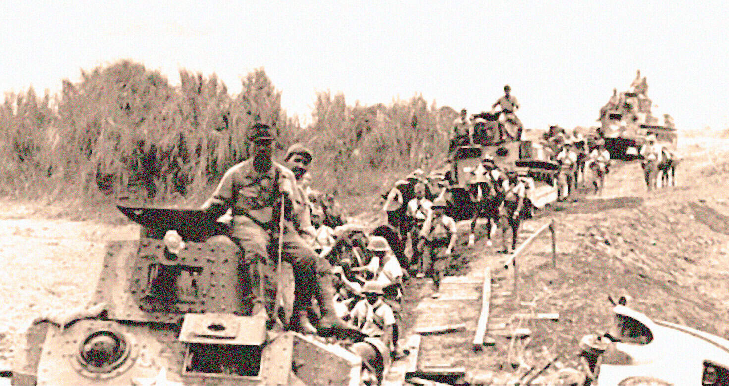 Soldiers riding a tank during wartime historical photo.