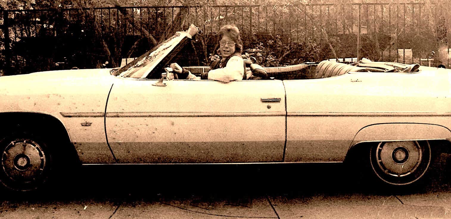 Old convertible car with woman smiling, vintage 1960s automobile, classic car nostalgia, retro vehicle photo for history and music archive.