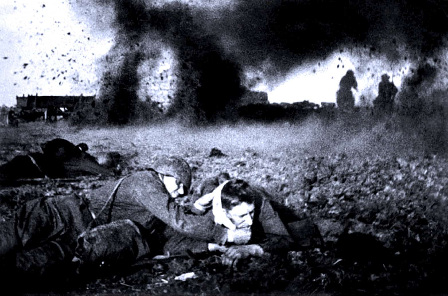 WWII soldiers resting amidst battlefield chaos with smoke and explosions in the background, capturing a historic moment of war and conflict.