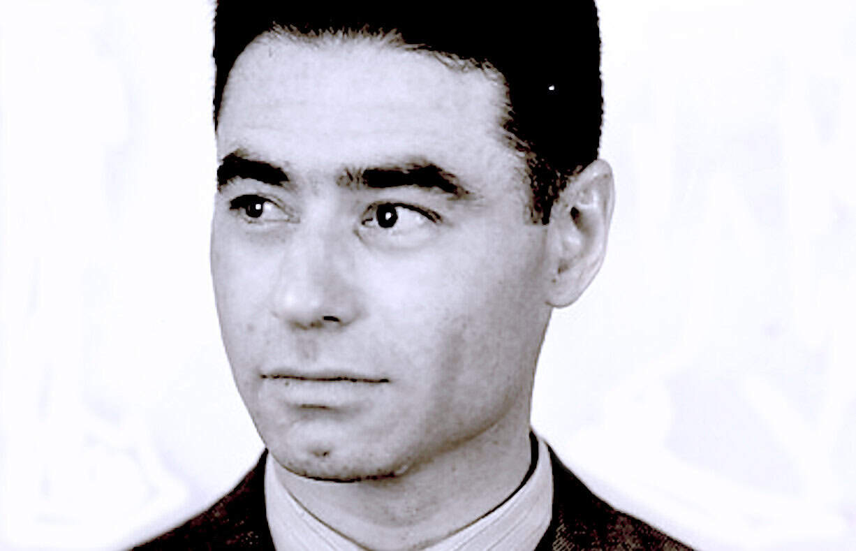 Black and white photograph of a young man with neatly styled hair, wearing a suit and tie, representing historical news and music archives from Past Daily.