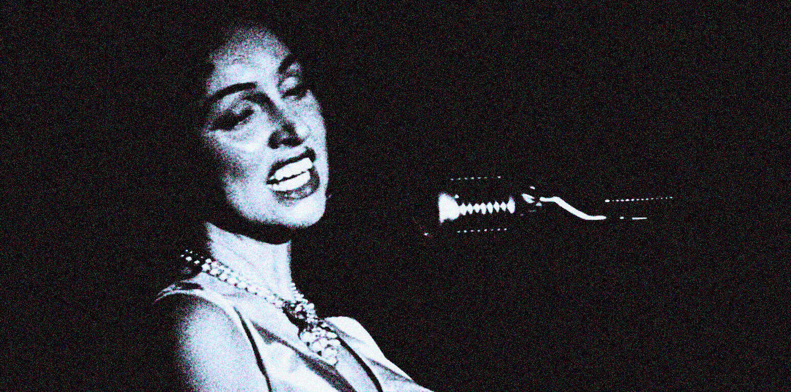 Vintage black-and-white photo of Ella Fitzgerald singing into a microphone, highlighting iconic jazz and music history from Past Daily sound archive.