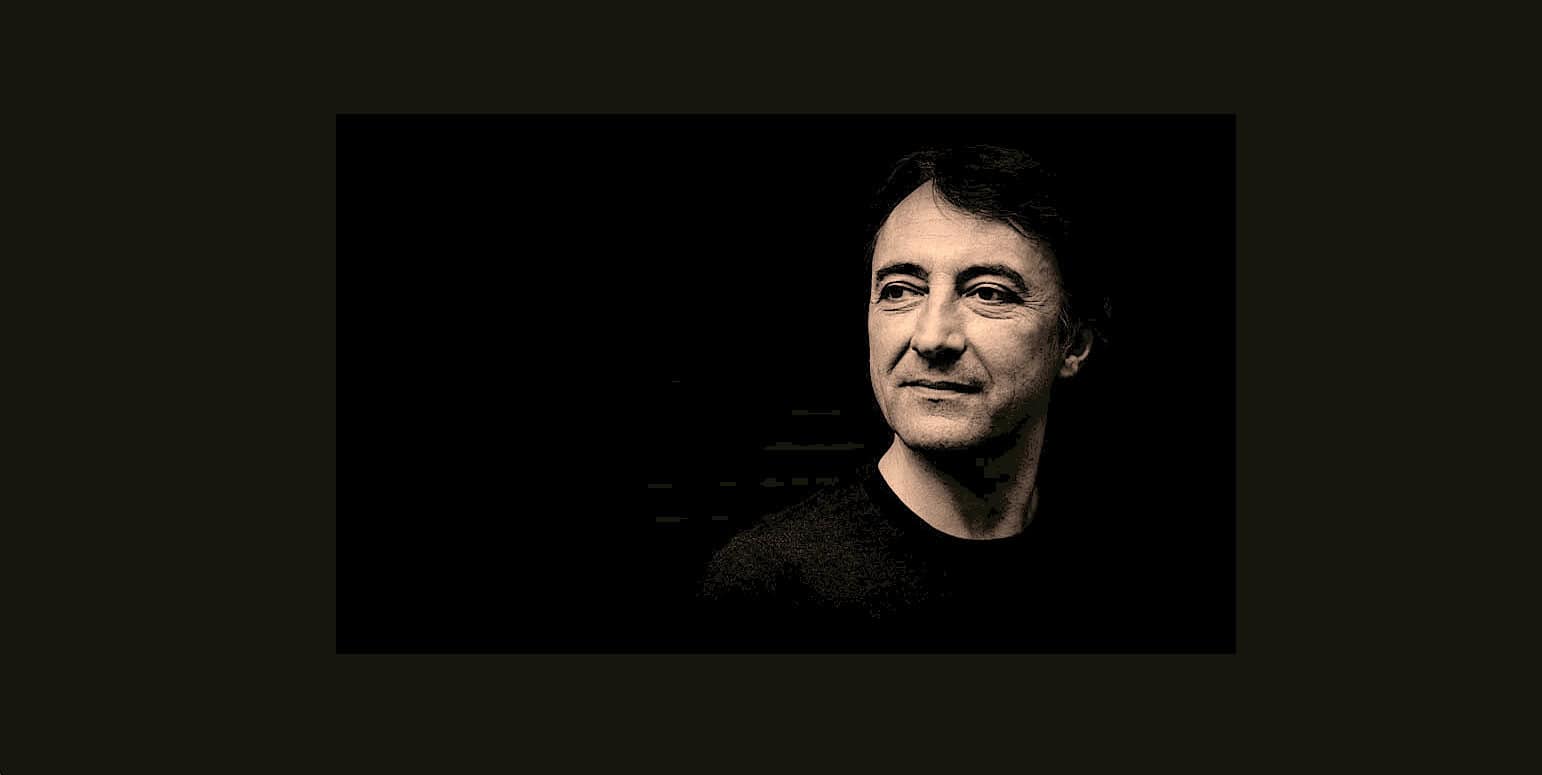 Silent black and white portrait of a man with dark hair, highlighting his contemplative expression, representing a history and music sound archive emphasizing news, history, and music recordings.