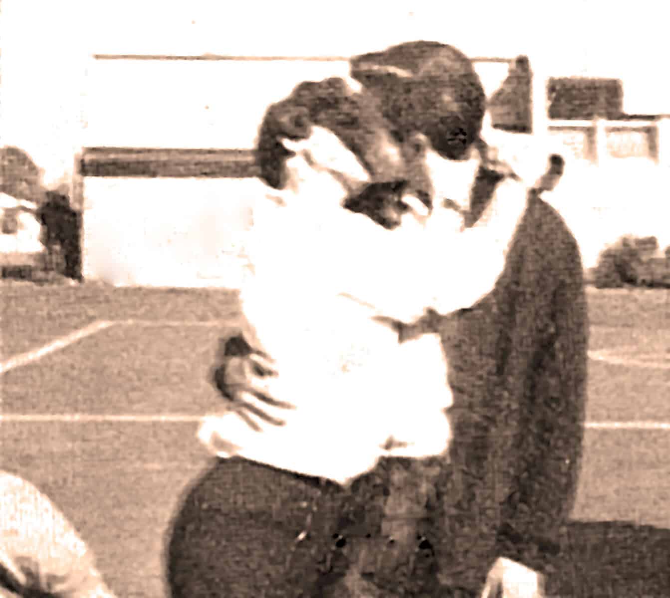 Vintage black and white photo of two young boys in sports uniforms, one wearing sunglasses, on a schoolyard or sports field, capturing a moment from past daily news, history, and music archives.