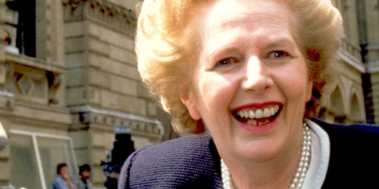 Untitled image of a smiling woman with blonde hair and pearl necklace outside historical building in New York City.