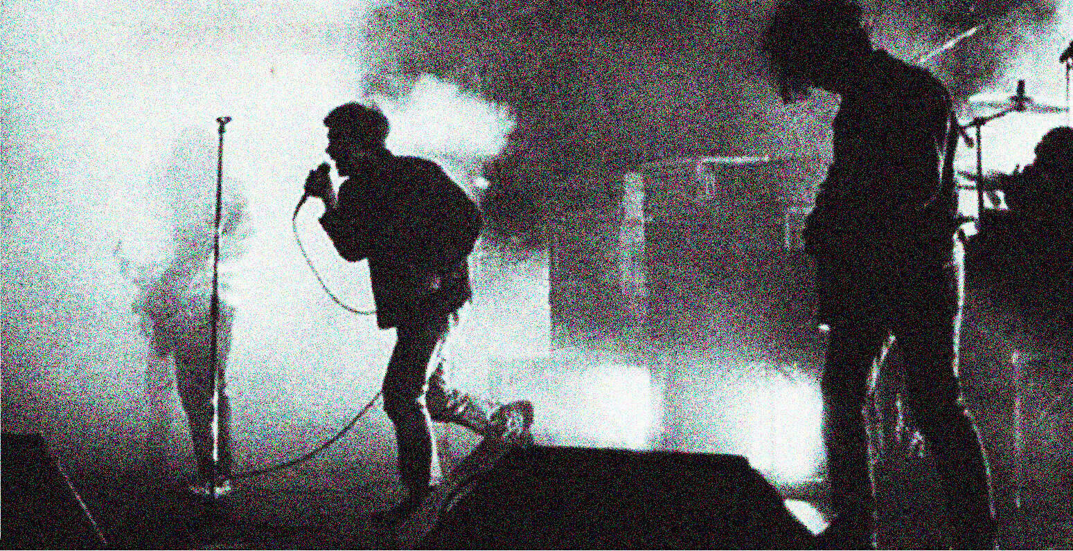 Rock band performing live on stage with smoke effects and dynamic lighting at Past Daily music archive event, showcasing historical news, music, and entertainment recordings.