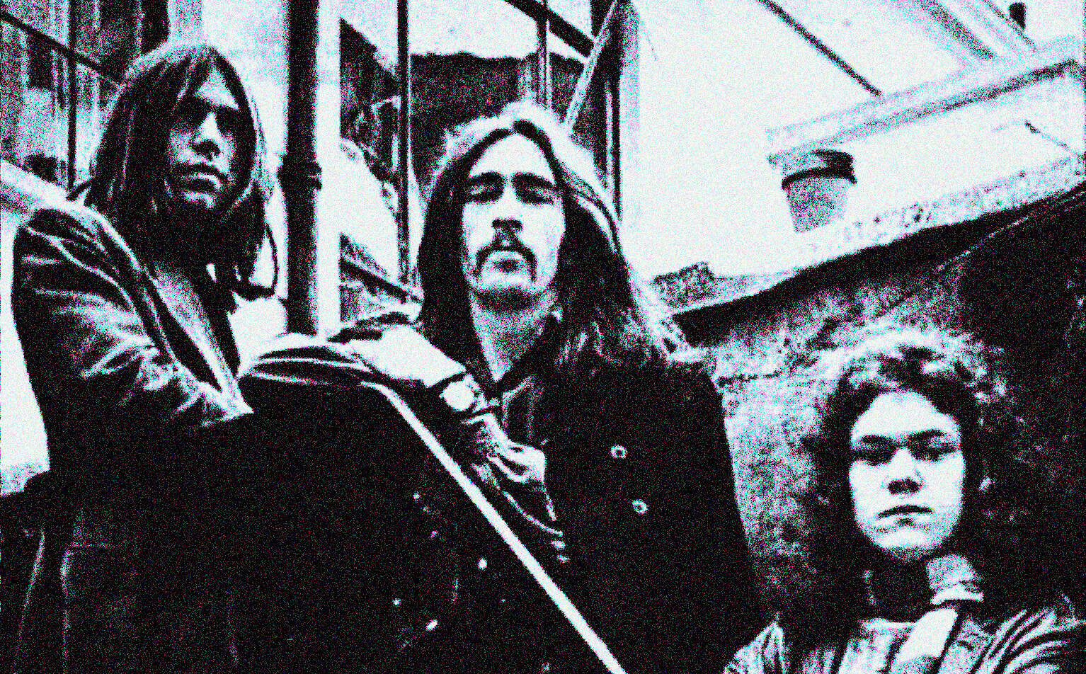 Vintage black and white photo of the band Nirvana, featuring Kurt Cobain, Krist Novoselic, and Dave Grohl, outside an urban building, iconic grunge music scene, nostalgic music history image.