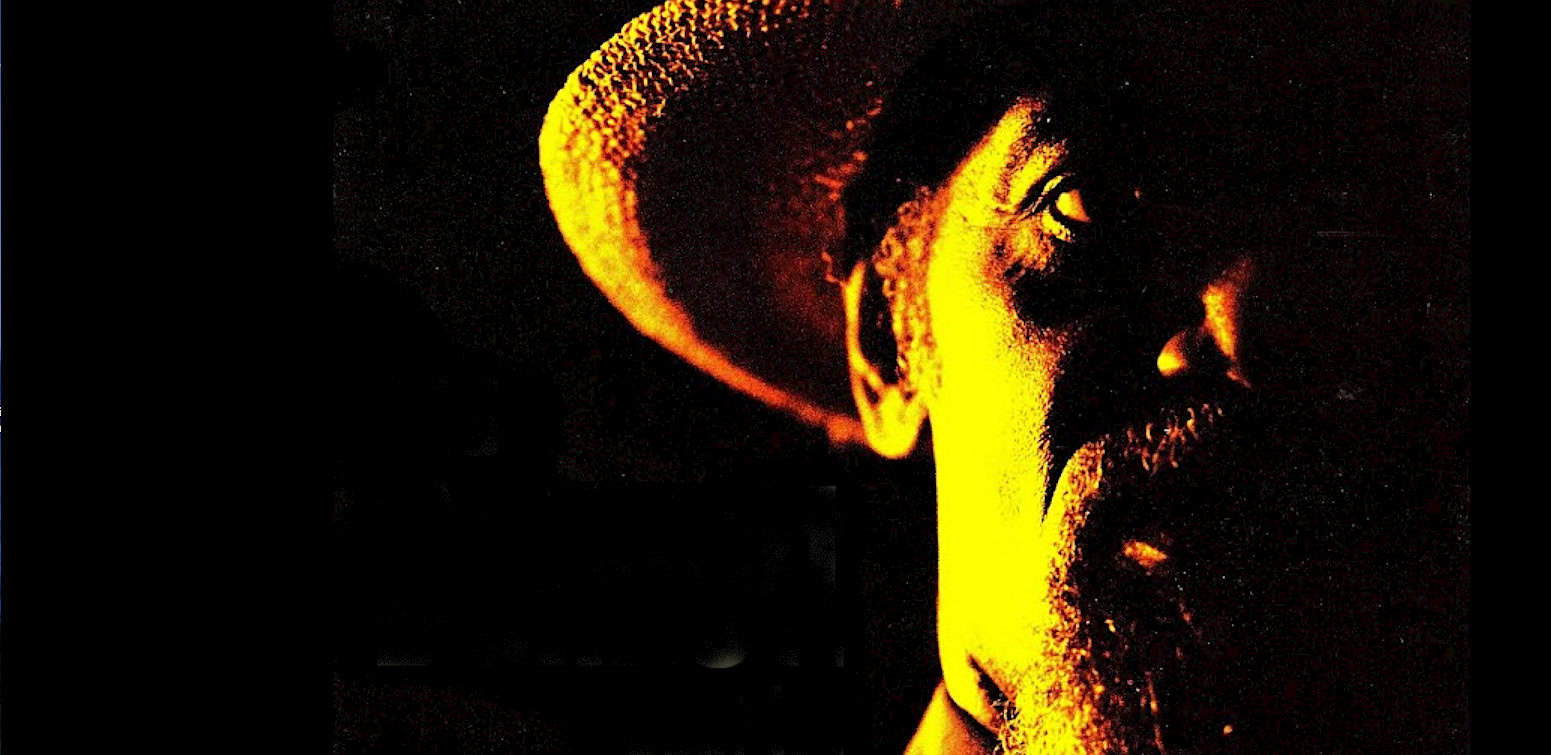 Beard man wearing a hat in dramatic lighting, vintage style, black background, music and history archive, retro portrait, historic sound recordings.