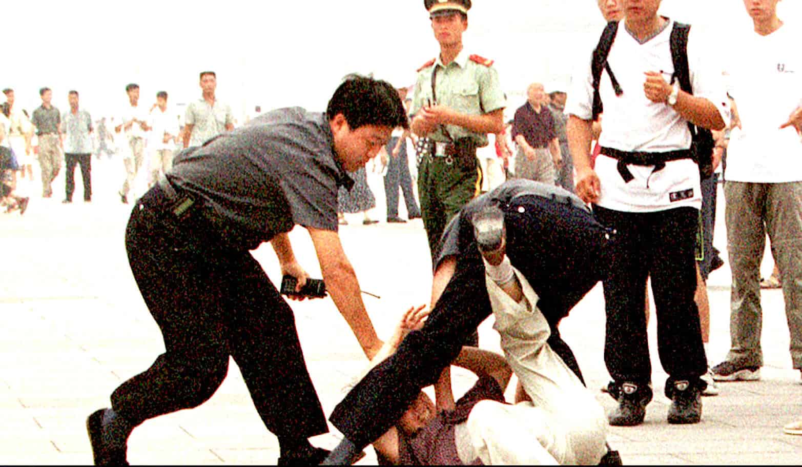 Man being detained during protest, police arresting individual on street, civil unrest, law enforcement action, public demonstration, social upheaval, news footage, historical event, political protest, security forces at work.