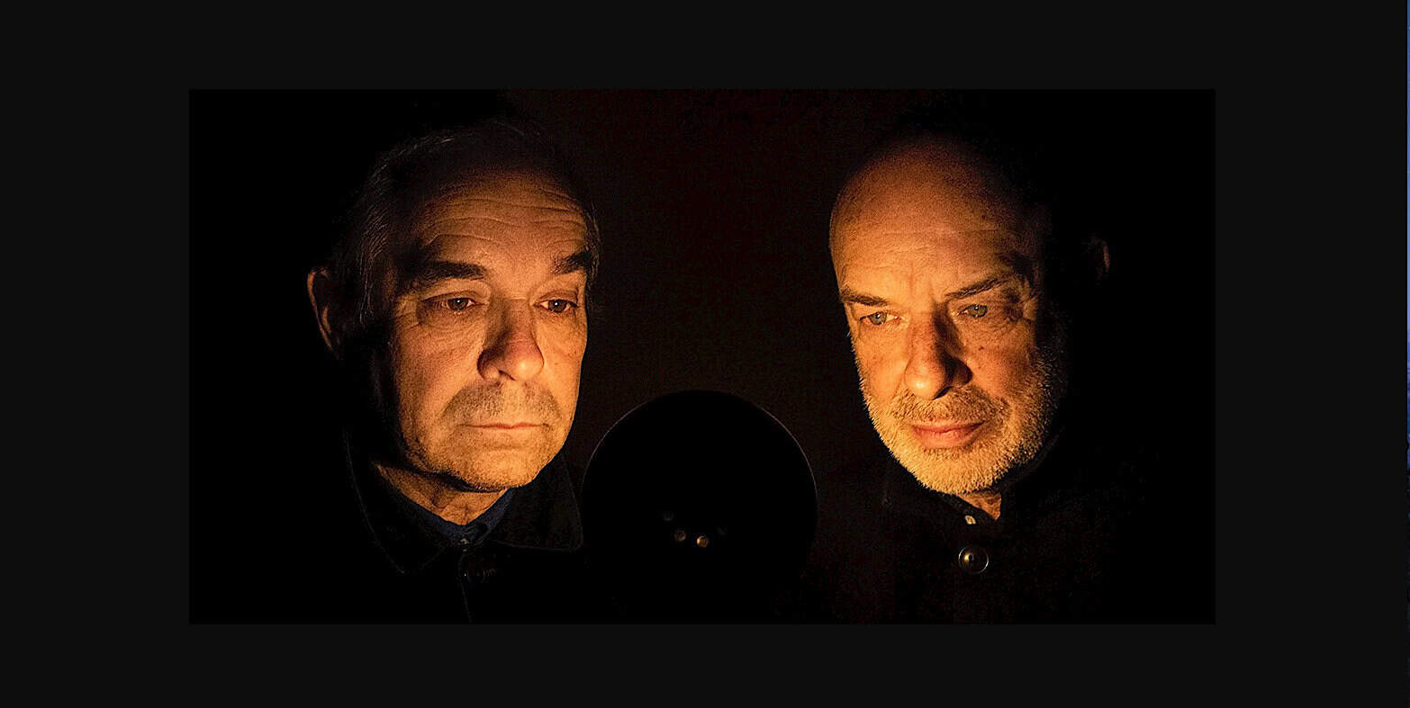 Vintage radio hosts recording in a dark studio with microphone for history, news, and music archival content.