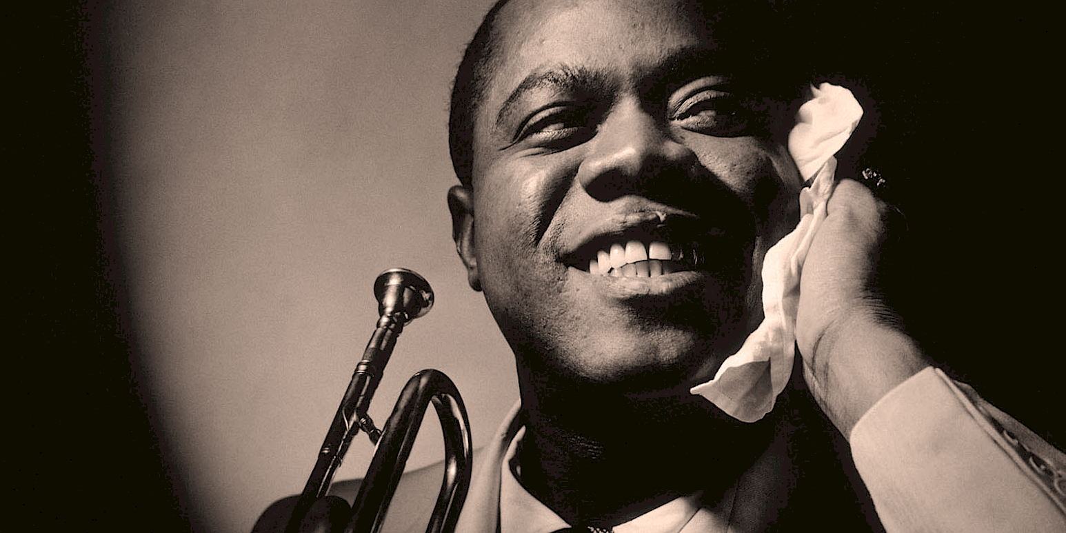 Vintage black and white photo of a jazz musician smiling happily while holding a trumpet and a tissue, capturing the essence of classic music and historical sound archives.