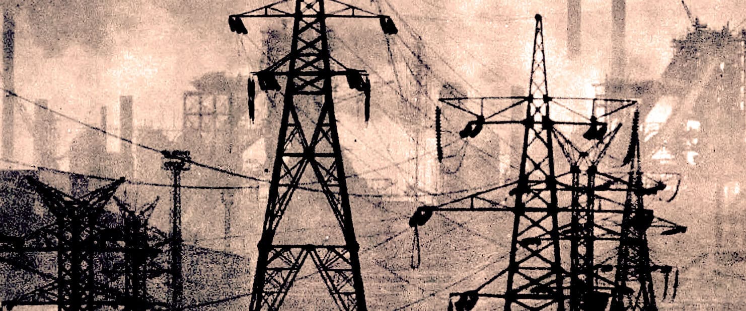 High-voltage electrical power lines and transmission towers in an industrial setting for energy transmission.