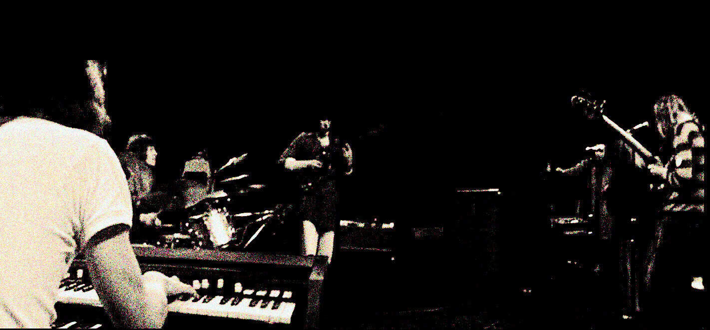 A sound archive of musicians practicing and recording music, featuring a band playing instruments in a dark studio setting with vintage recording equipment, highlighting history and music archival content.
