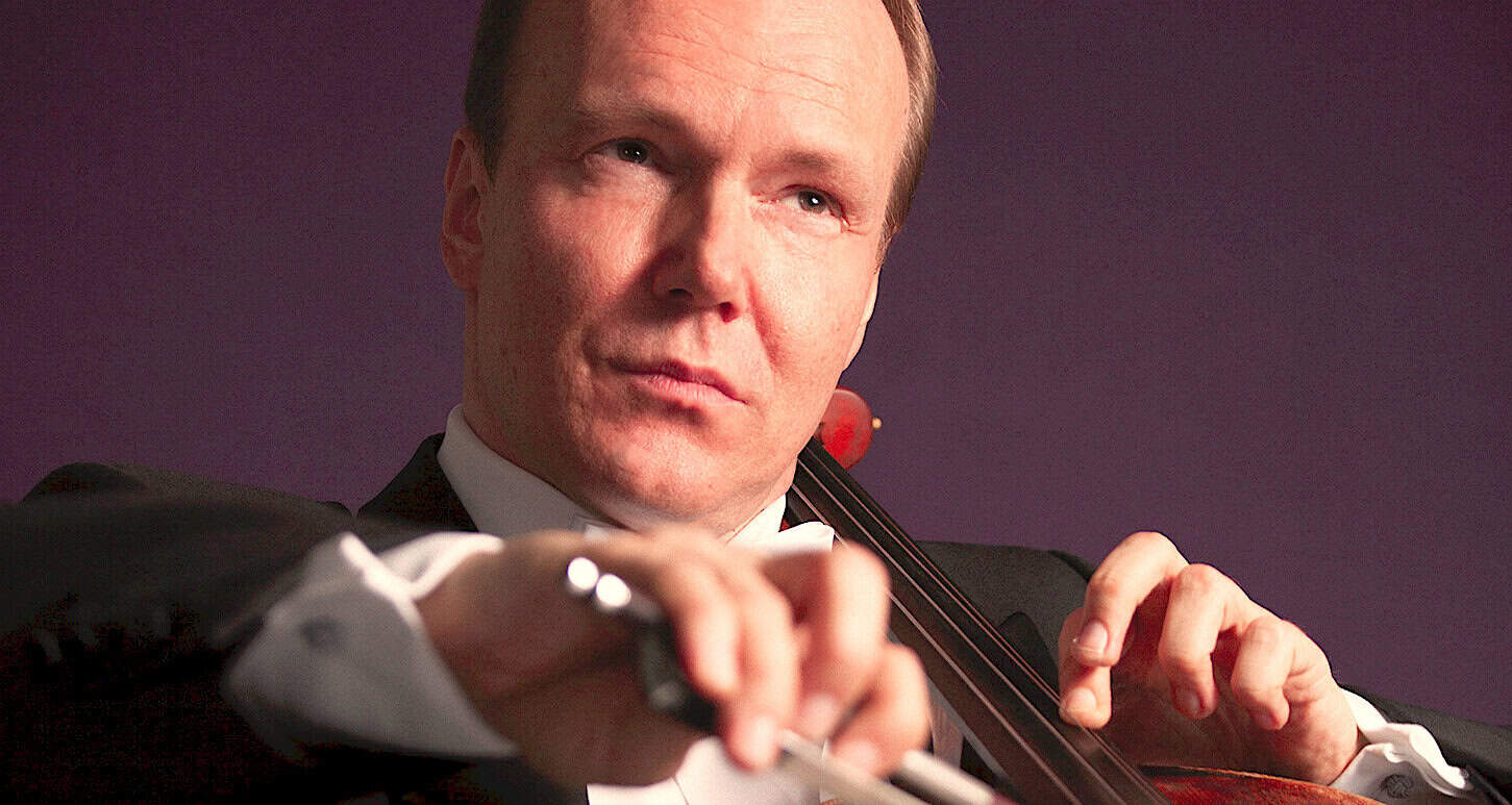 Renowned classical violinist playing his instrument in a professional performance setting, showcasing musical talent and artistry.