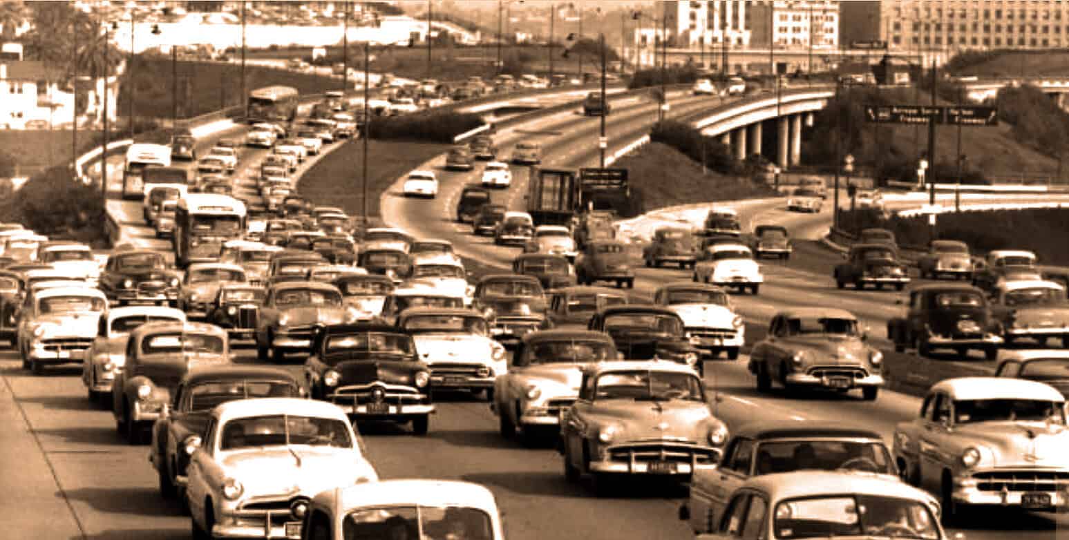 Vintage cars on an urban highway, illustrating mid-20th century transportation and traffic history, with a sepia tone image emphasizing historical relevance to news archives.