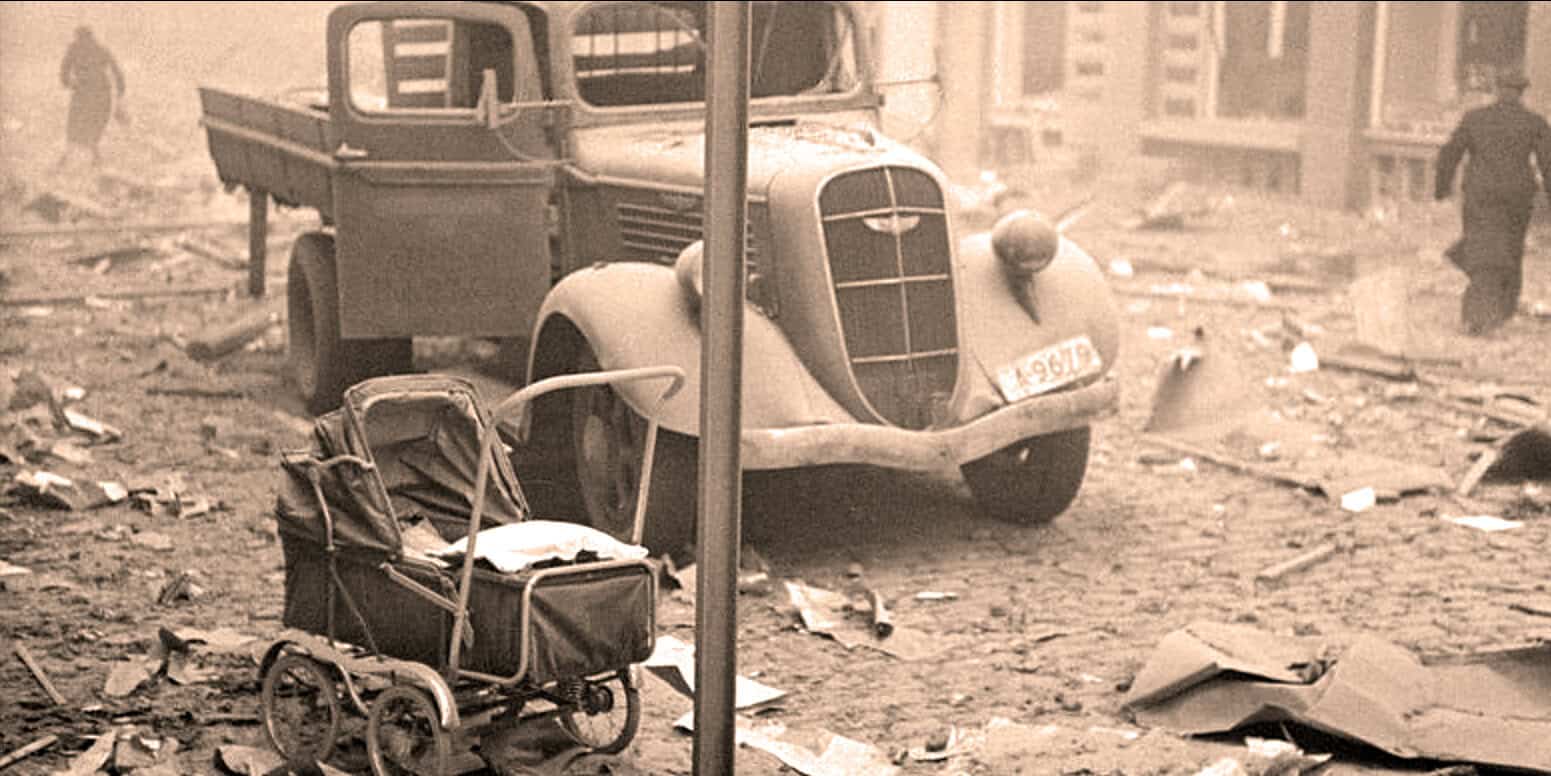 Burned vintage car and abandoned baby stroller amidst urban destruction after disaster; historical news archive focusing on tragedy, chaos, and historic events.