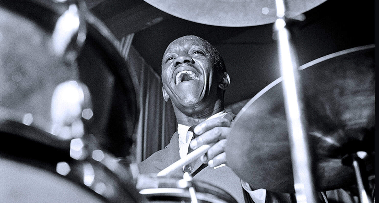 Vintage jazz musician passionately playing drums in a live performance.