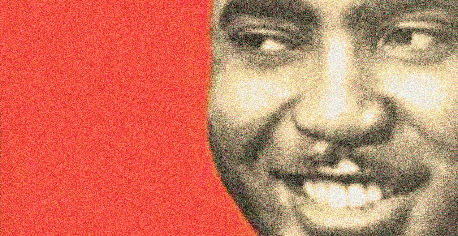 Vintage black and white photo of a smiling man with a red background, highlighting historical news, music archives, and audio recordings from Past Daily.