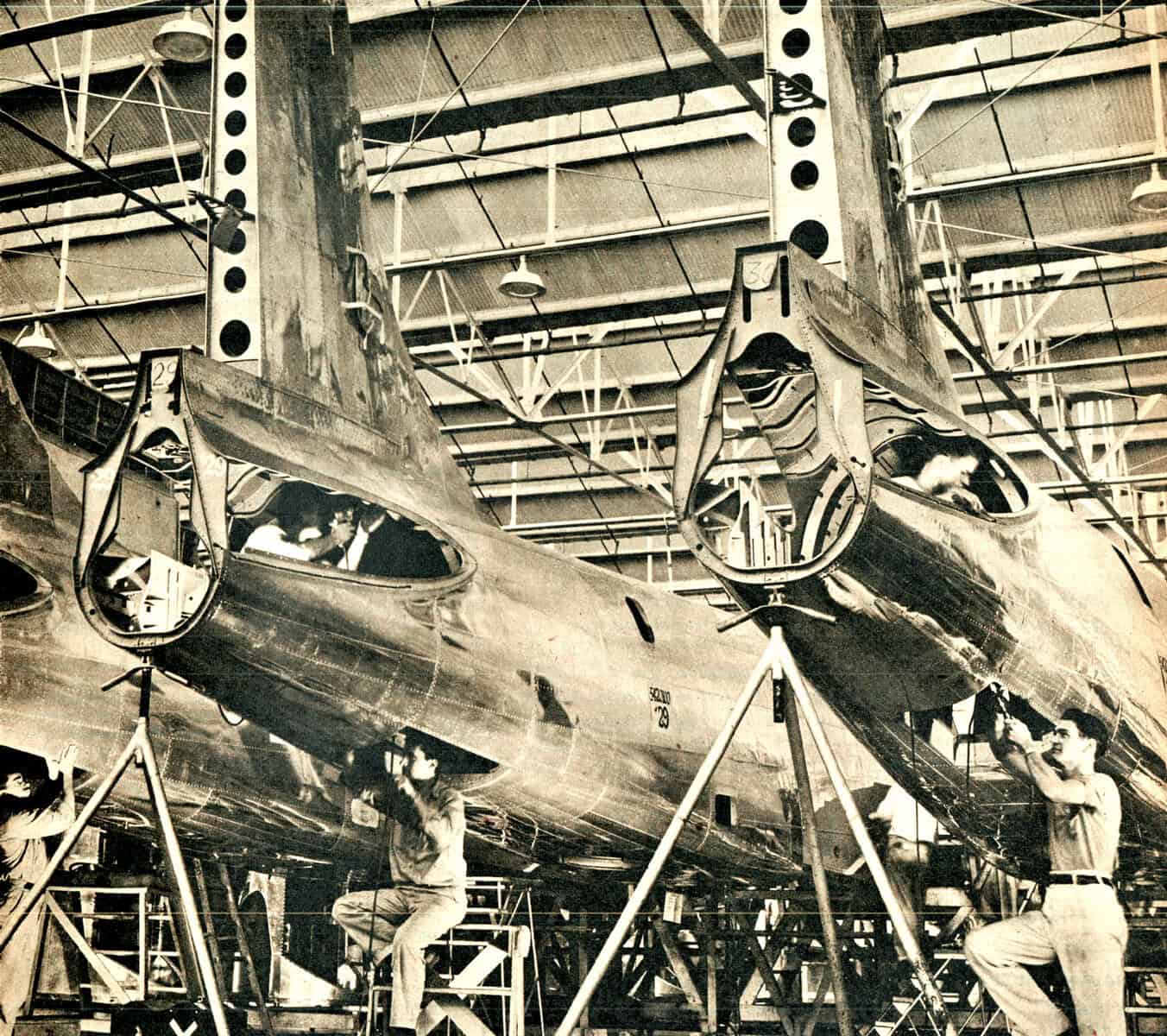 Assembly line workers working on fighter jet construction in an aerospace manufacturing facility, illustrating industrial history and advanced aircraft production techniques.