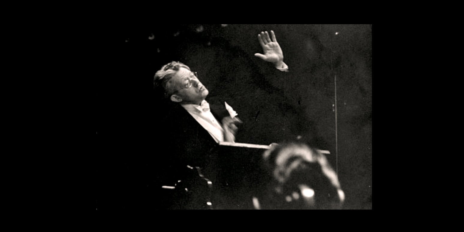 Pianist conducting in black and white during a historic music performance, vintage jazz or classical concert scene, vintage music archive, historic live music event image.