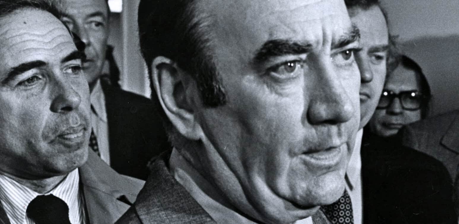 Historic black and white photo of political leaders, including President Ronald Reagan, during a news conference or event, highlighting historical news, politics, and media coverage.