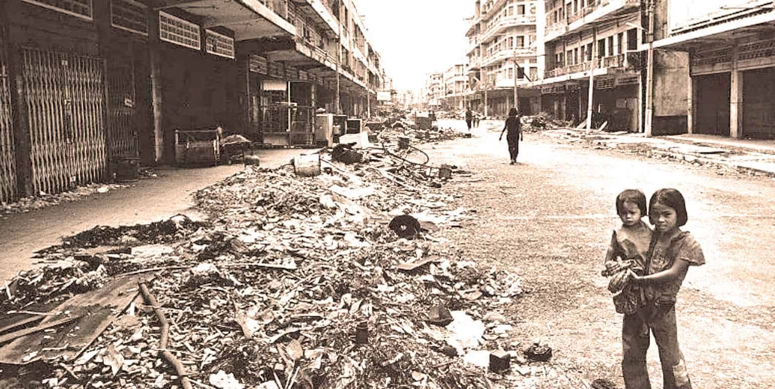Ruined urban street scene with debris and children standing in the foreground, capturing impacts of war or disaster, highlighting historical news and crisis coverage.