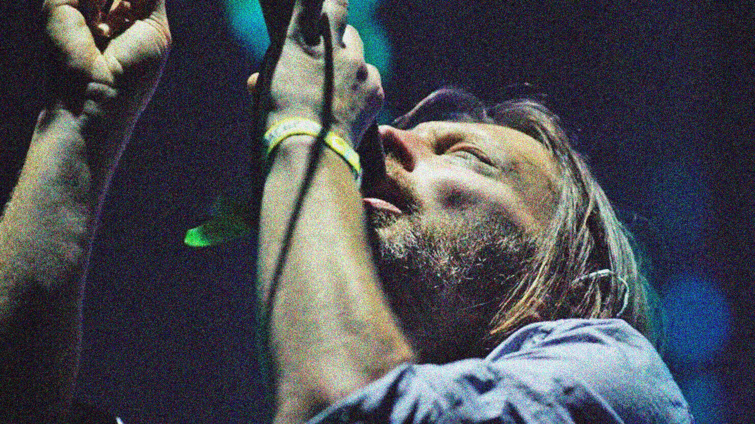 Photographer singing passionately into a microphone during a live music performance, capturing the spirit of musical history and news archive at Past Daily.