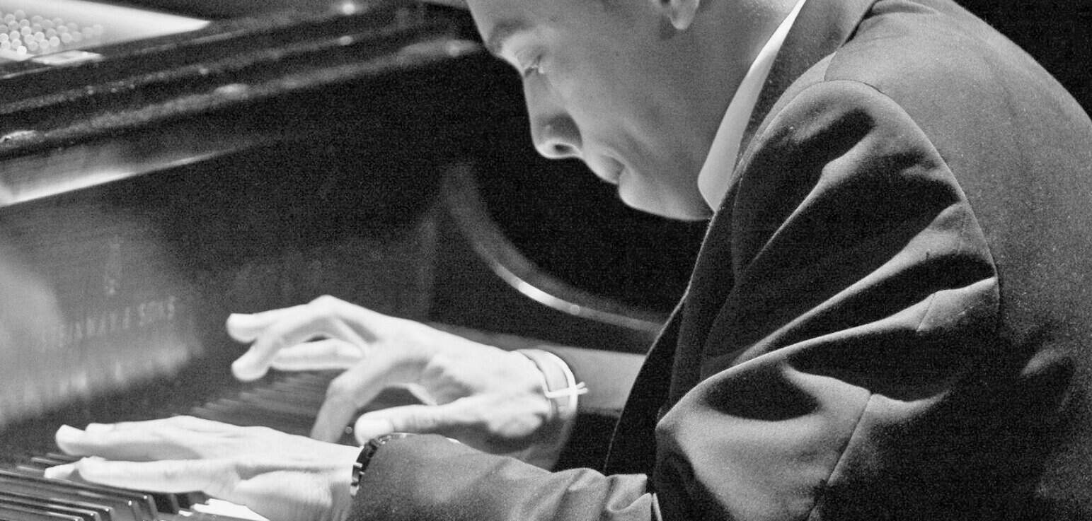 Pianist playing grand piano, black and white music archive, history, news, and classic tunes, vintage jazz performance, live music, historic concert scene.