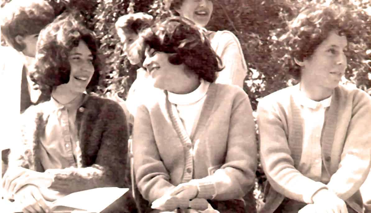 People laughing and talking outdoors, vintage photo capturing joyful moments among friends, representing nostalgia, friendship, and community in a classic black-and-white style.