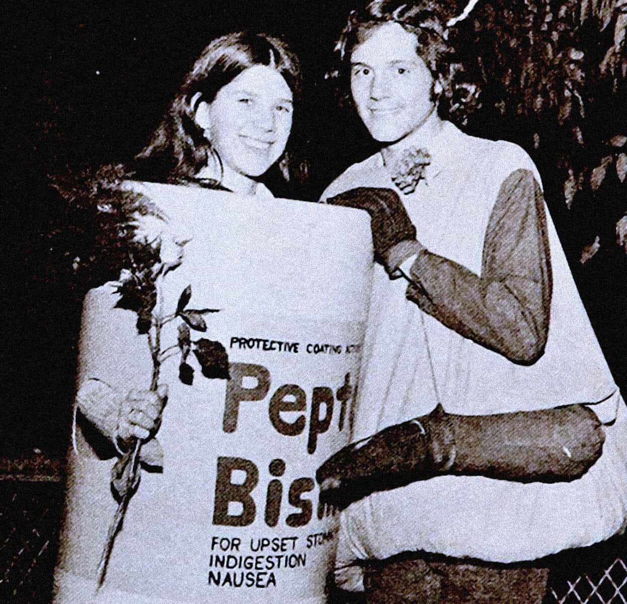 Historical protest photo featuring two young people holding a Pepto Bismol banner for upset stomach indigestion nausea, vintage black and white image, news and music archive image from Past Daily.