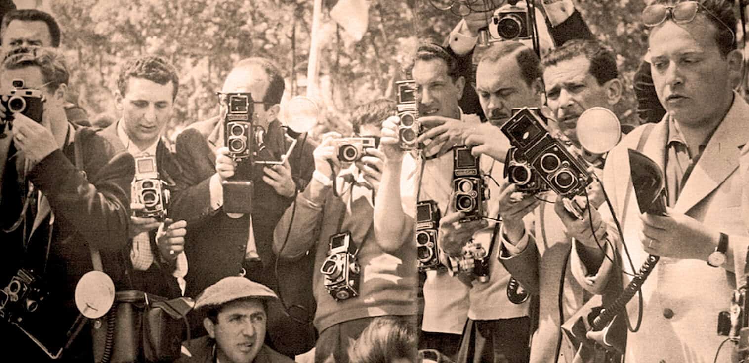 Crowd of journalists with vintage cameras documenting news event, historical press coverage, media reporting, photojournalism, news photography, vintage media technology, 1950s press gathering.