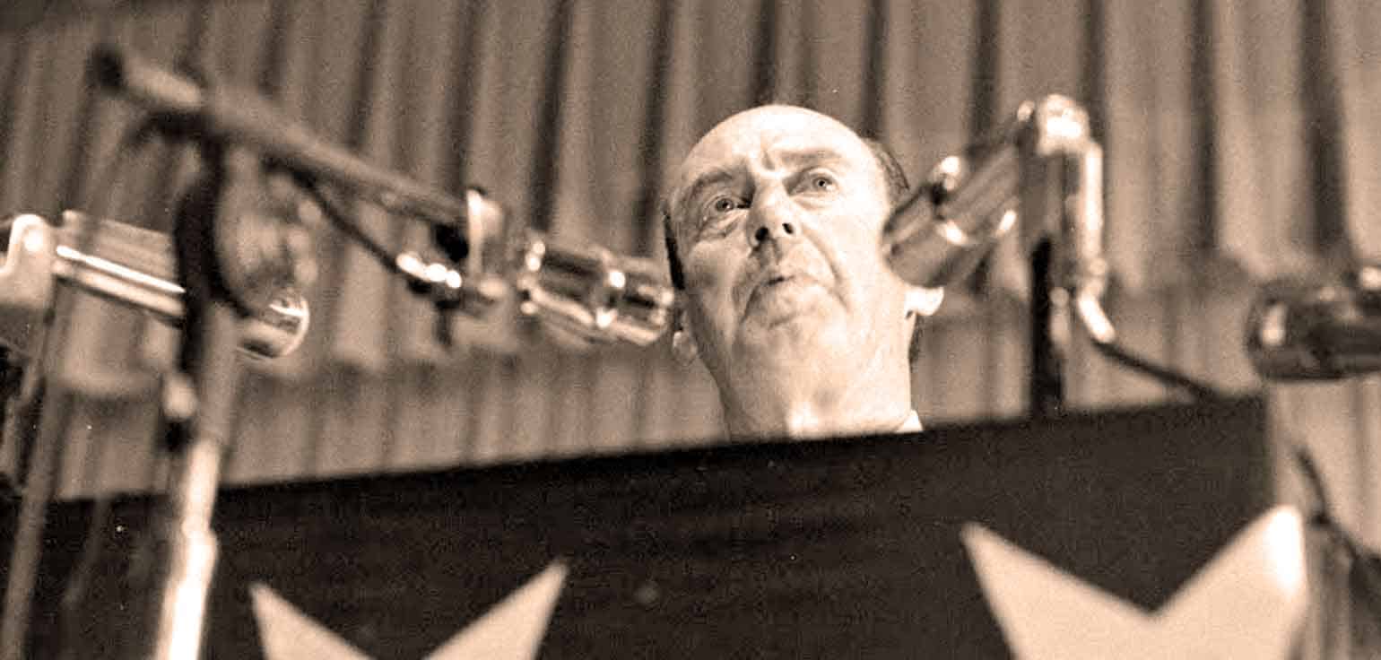 Announcer recording at vintage microphone in sound studio for historical news and music archives.