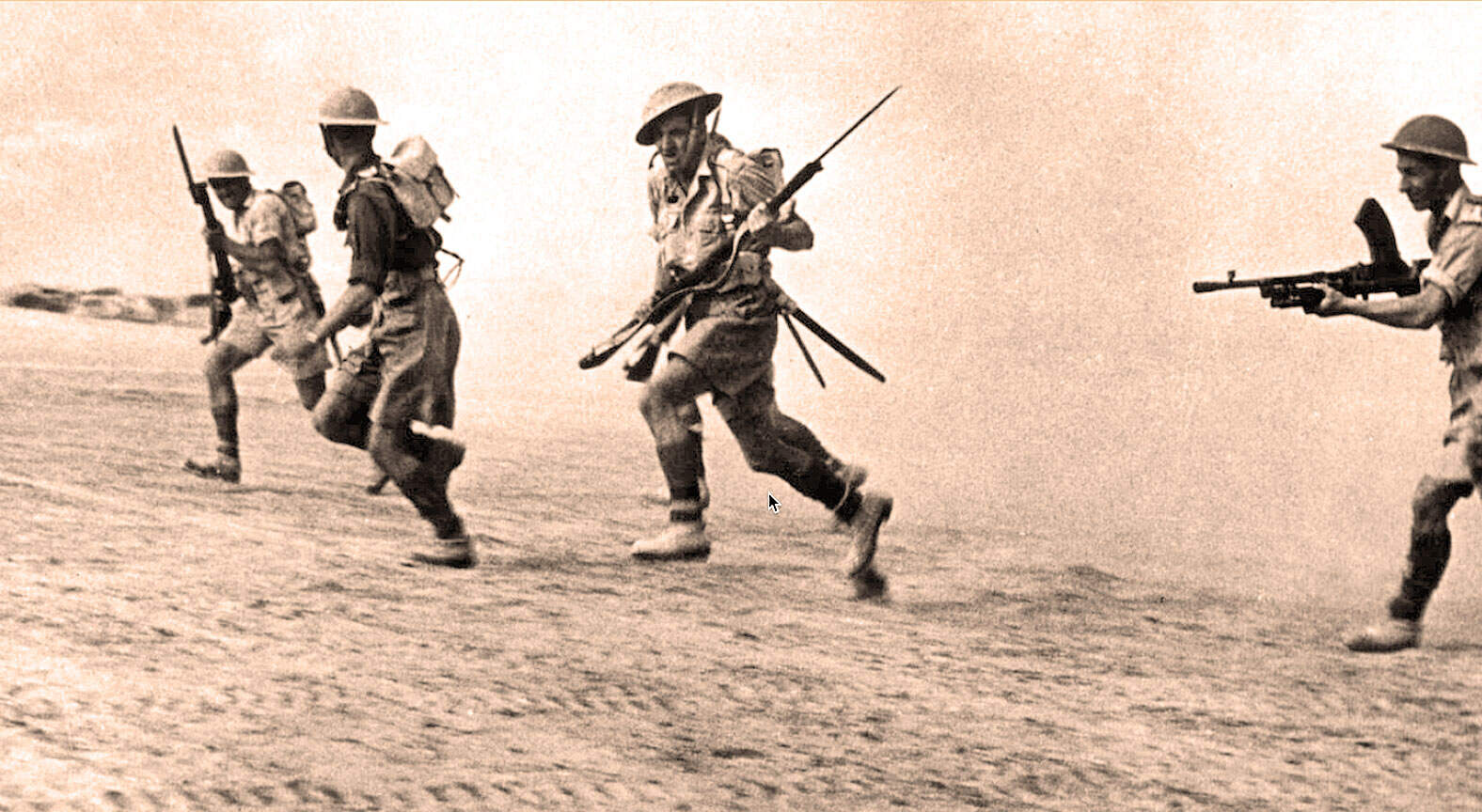 Soldiers running across desert terrain during wartime, carrying weapons and gear, historical military scene, black-and-white photo.