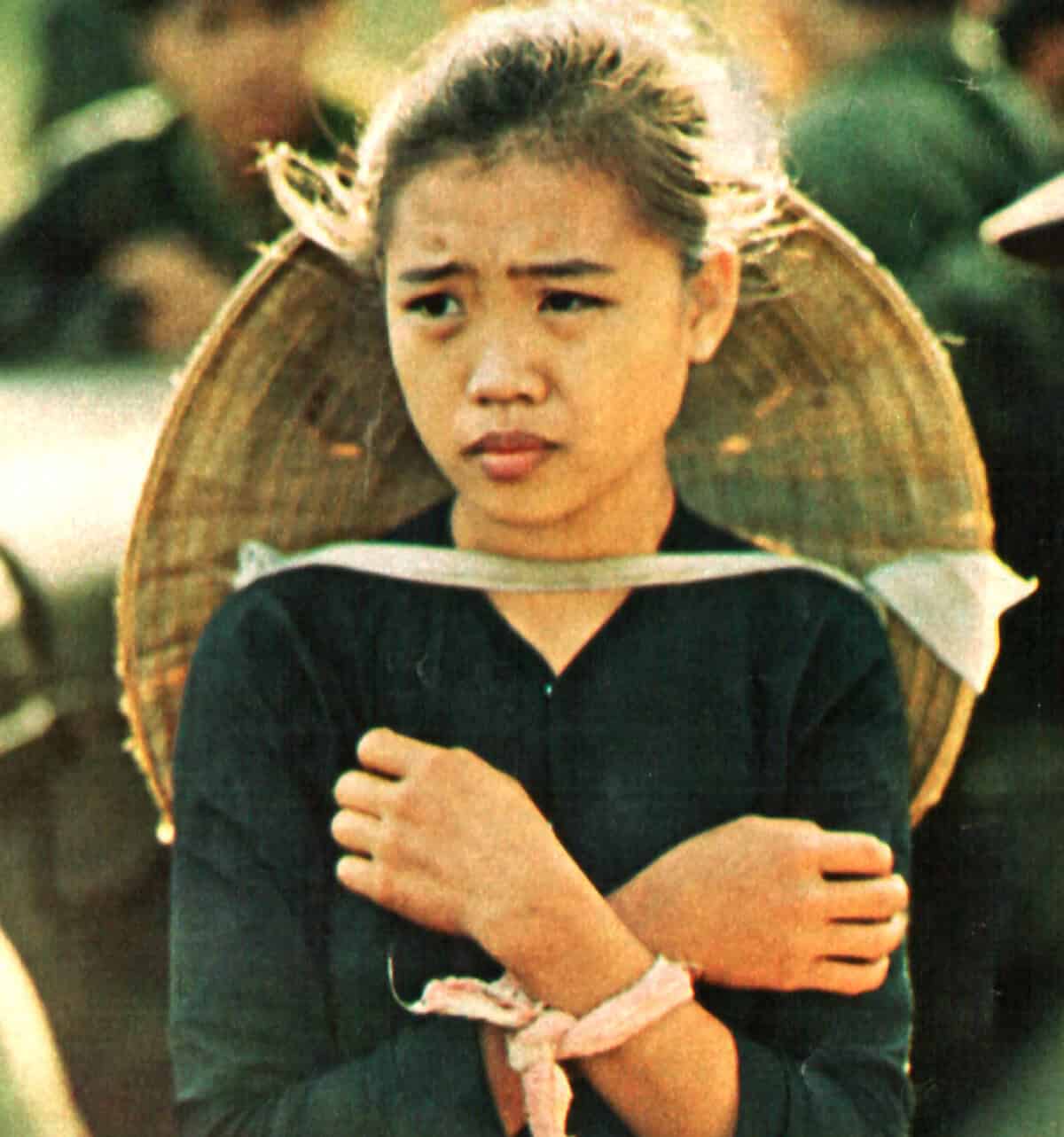 Old photo of a young woman with traditional Asian attire, carrying a woven hat on her back, reflecting cultural heritage and history, with nostalgic and historical significance.