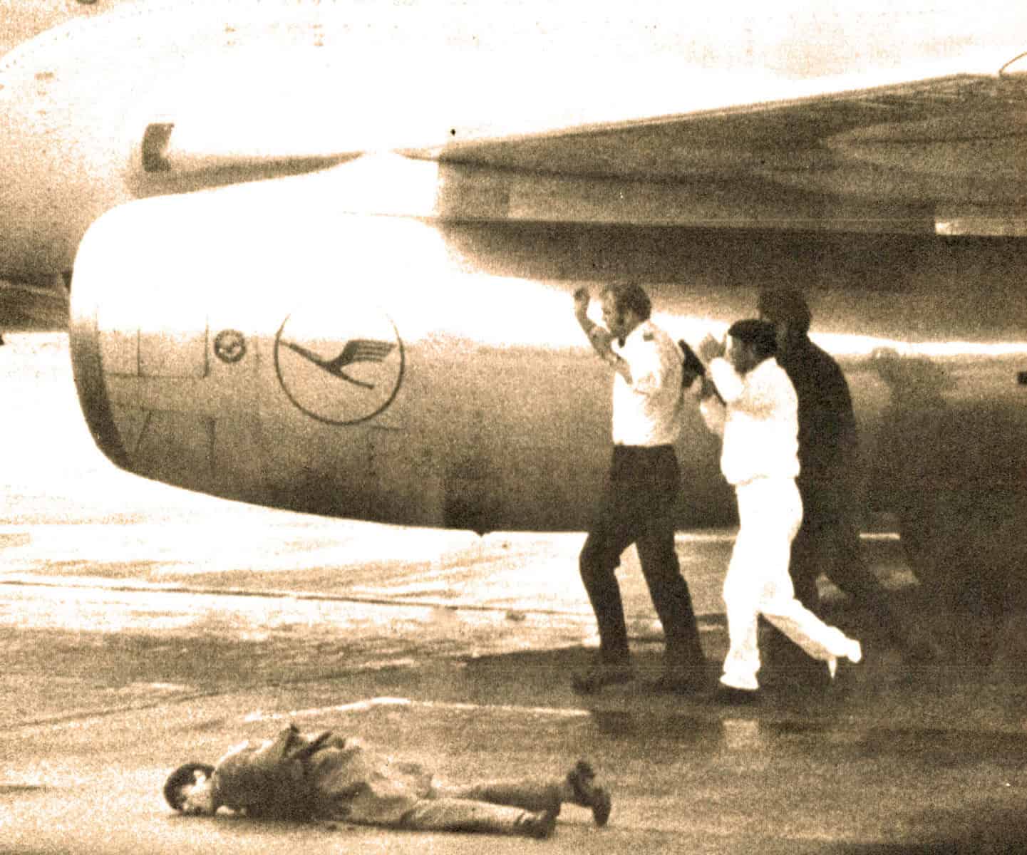 Lufthansa airplane being boarded by passengers, with a person lying on the ground nearby, illustrating air travel, airline operations, and airport scenes in vintage style.